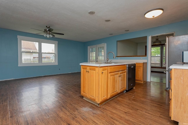 kitchen featuring ceiling fan, light countertops, an island with sink, dark wood-style floors, and dishwashing machine
