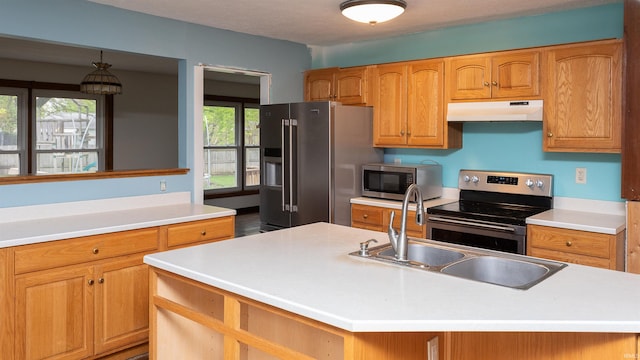 kitchen featuring a center island with sink, light countertops, under cabinet range hood, a sink, and stainless steel appliances