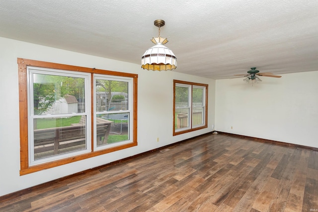 spare room with a ceiling fan, baseboards, a healthy amount of sunlight, and dark wood-type flooring