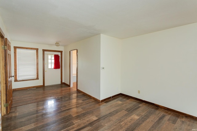 spare room featuring baseboards and dark wood-type flooring