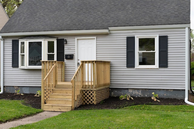 entrance to property with a lawn and roof with shingles