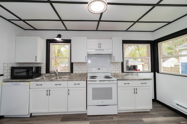 kitchen with white cabinets, baseboard heating, a sink, white appliances, and under cabinet range hood