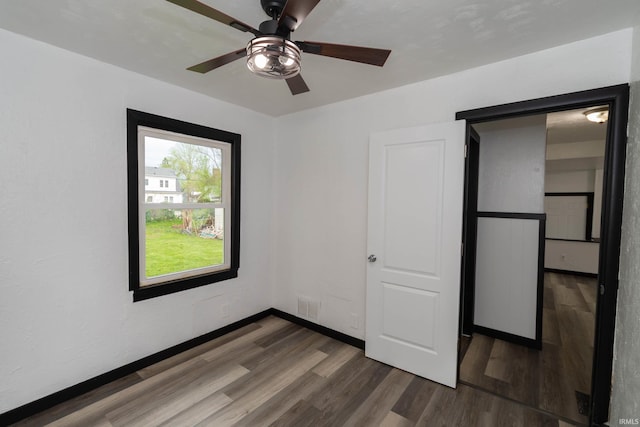 unfurnished bedroom featuring ceiling fan, baseboards, visible vents, and wood finished floors