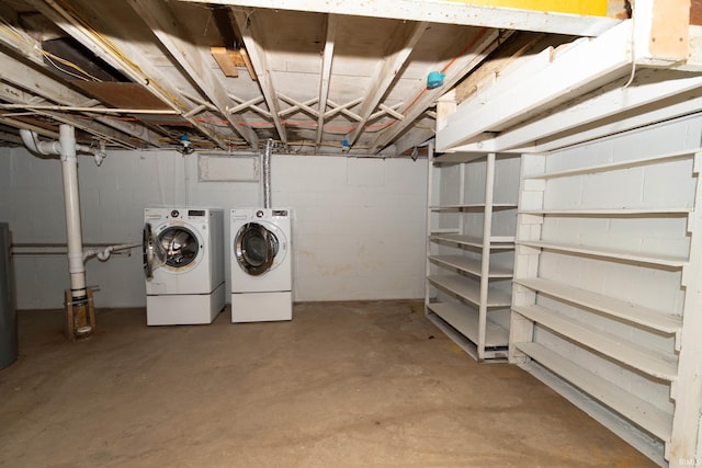 clothes washing area with concrete block wall, laundry area, and independent washer and dryer