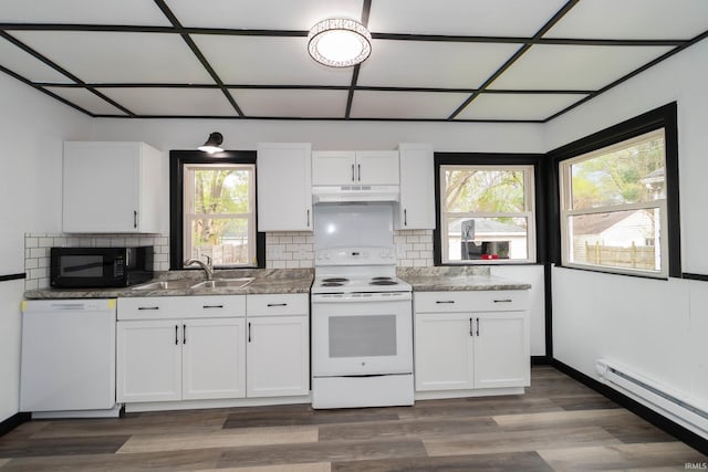 kitchen with backsplash, a sink, a baseboard radiator, under cabinet range hood, and white appliances