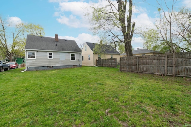 rear view of property with fence, a chimney, and a yard