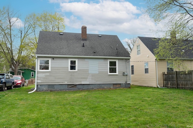 back of house with fence, a chimney, and a lawn