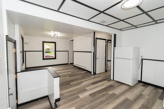 interior space featuring a baseboard heating unit, wood finished floors, and visible vents