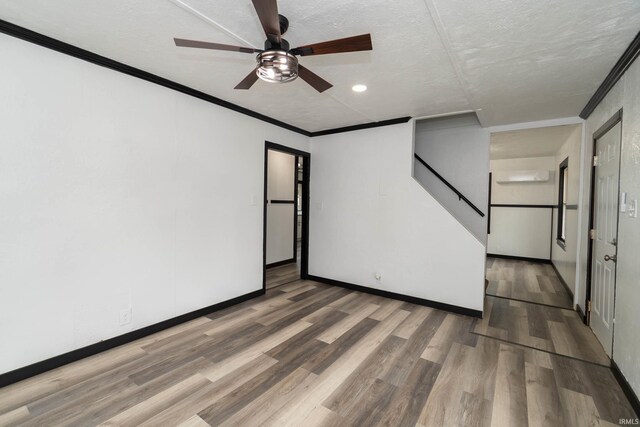 empty room featuring ceiling fan, wood finished floors, and stairway