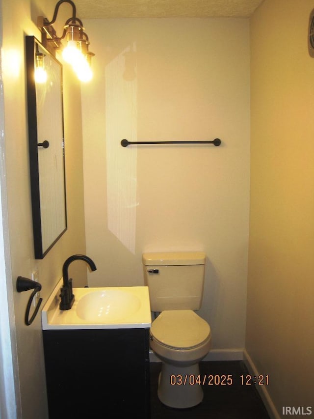 bathroom with toilet, baseboards, and vanity