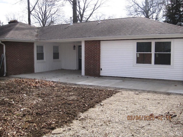 back of property featuring a patio, a shingled roof, and brick siding