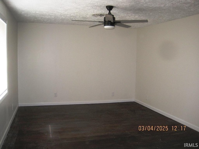 empty room with a ceiling fan, a textured ceiling, dark wood finished floors, and baseboards