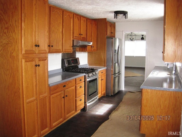 kitchen with dark wood finished floors, brown cabinetry, stainless steel appliances, backsplash, and under cabinet range hood