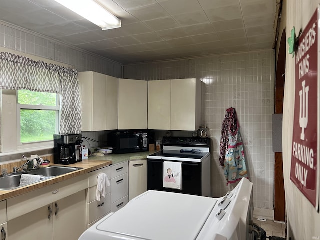 kitchen with light countertops, tile walls, a sink, and black appliances