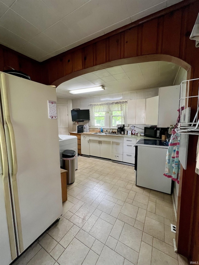 kitchen with freestanding refrigerator, black microwave, light countertops, white cabinets, and range