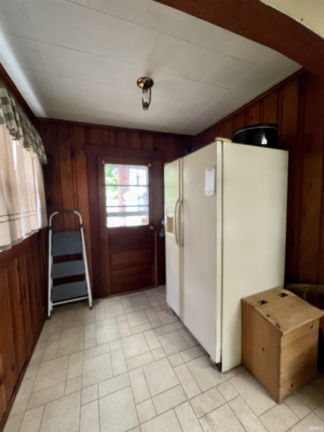 kitchen with wooden walls and white fridge with ice dispenser