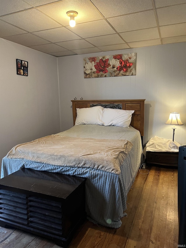 bedroom with wood-type flooring and a drop ceiling