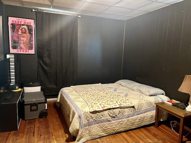 bedroom featuring wooden walls and hardwood / wood-style floors