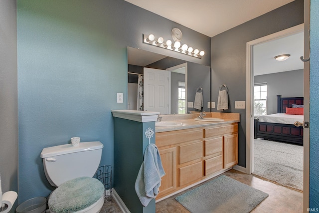 ensuite bathroom featuring double vanity, a sink, ensuite bathroom, and toilet