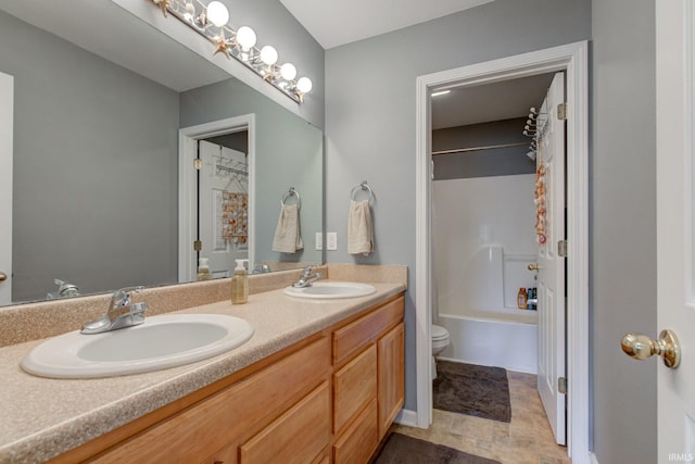 bathroom featuring double vanity, toilet,  shower combination, and a sink