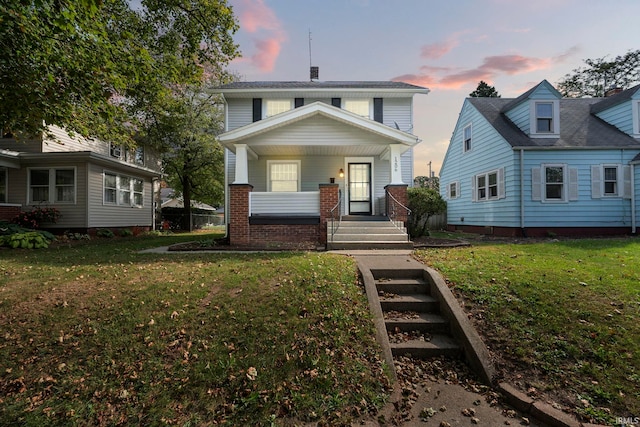view of front of property with covered porch and a yard