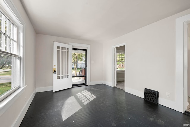 unfurnished room with visible vents, baseboards, and dark wood-style floors