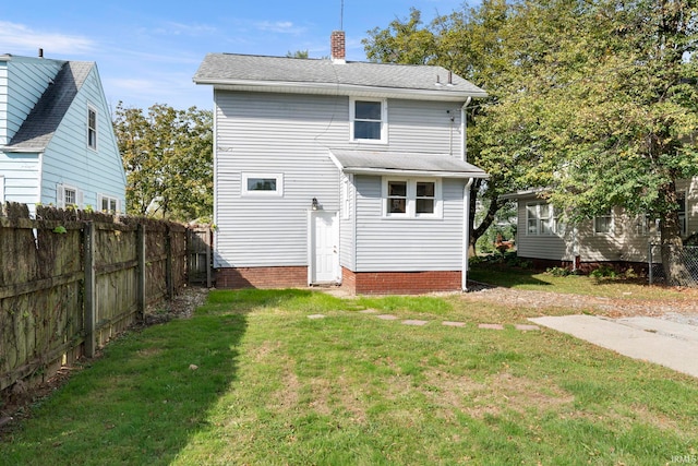 back of property with fence, a chimney, and a lawn