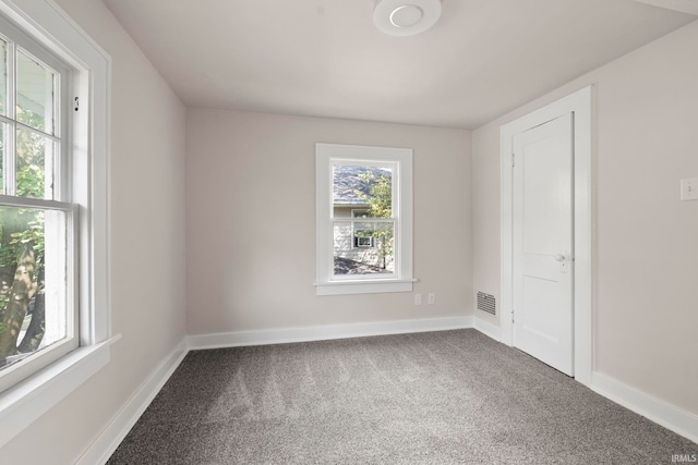 carpeted spare room featuring visible vents and baseboards