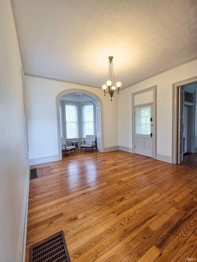 1106 E 5th St, Fowler, IN 47944 - unfurnished dining area with arched walkways, a chandelier, hardwood / wood-style floors, and a wealth of natural light