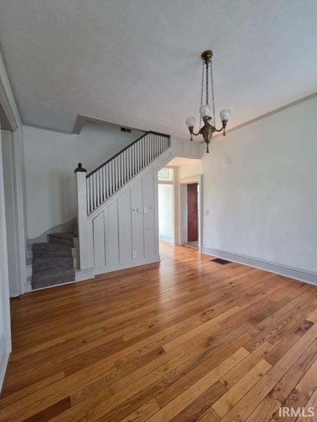 1106 E 5th St, Fowler, IN 47944 - unfurnished living room featuring wood-type flooring, baseboards, a chandelier, and stairway