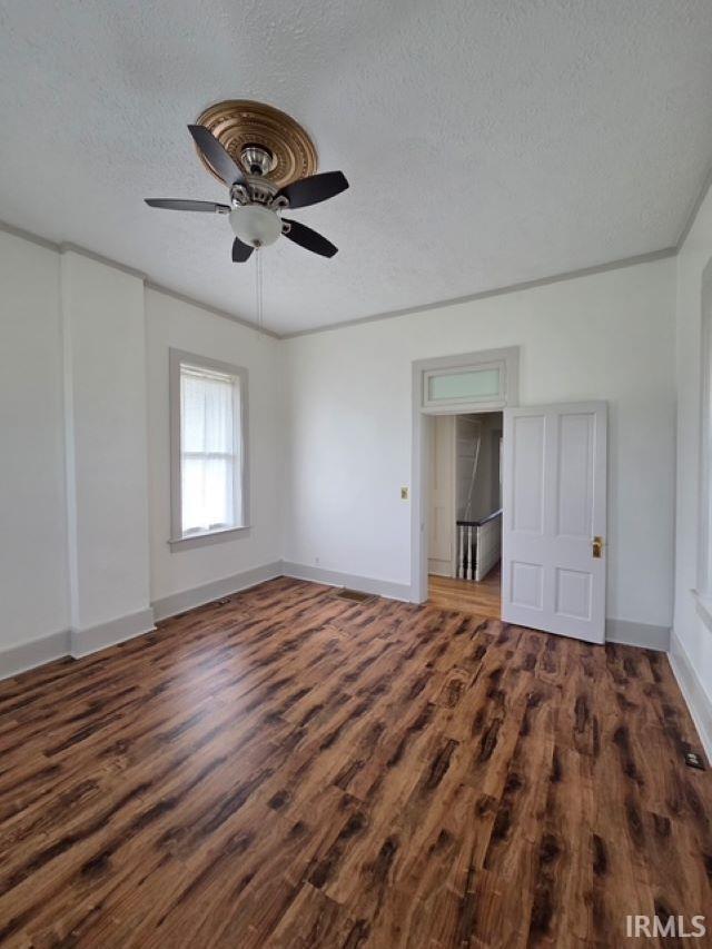 1106 E 5th St, Fowler, IN 47944 - unfurnished bedroom with baseboards, a textured ceiling, ceiling fan, and wood finished floors