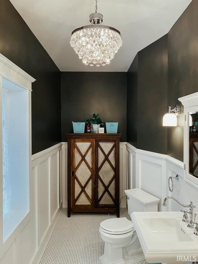 1106 E 5th St, Fowler, IN 47944 - half bathroom with wainscoting, a sink, toilet, a chandelier, and a decorative wall
