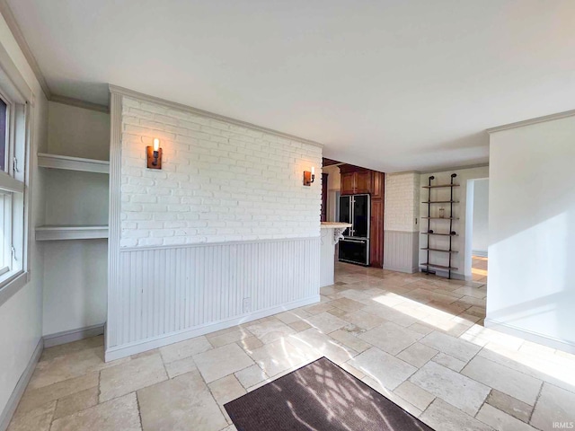 1106 E 5th St, Fowler, IN 47944 - spare room featuring brick wall, wainscoting, baseboards, and stone tile flooring