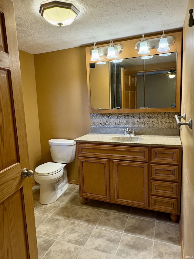 bathroom with ceiling fan, vanity, toilet, a textured ceiling, and tasteful backsplash