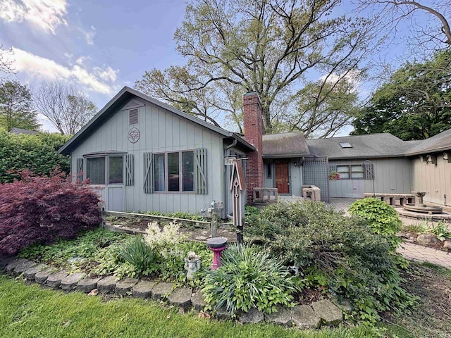 ranch-style home featuring central AC unit, board and batten siding, and a chimney