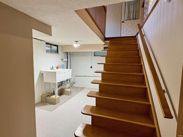 staircase with concrete block wall and a textured ceiling