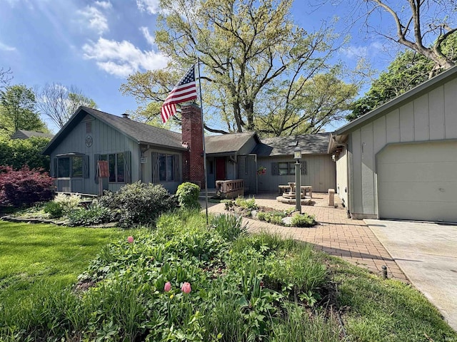 view of front of home featuring an attached garage, a chimney, and driveway