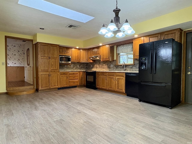 kitchen with an inviting chandelier, brown cabinetry, visible vents, light wood finished floors, and black appliances