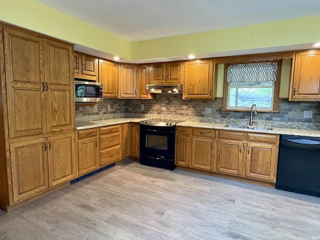 kitchen featuring a sink, brown cabinetry, tasteful backsplash, under cabinet range hood, and black appliances