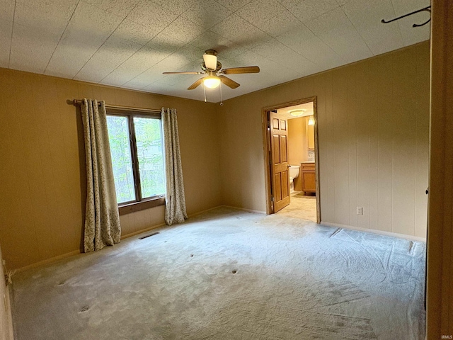 unfurnished room with a ceiling fan, light colored carpet, visible vents, and baseboards