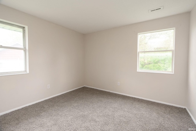 carpeted empty room featuring baseboards and visible vents