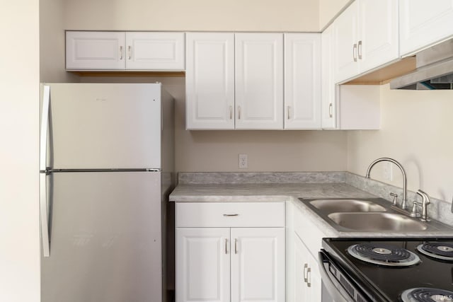 kitchen with freestanding refrigerator, a sink, white cabinetry, and light countertops