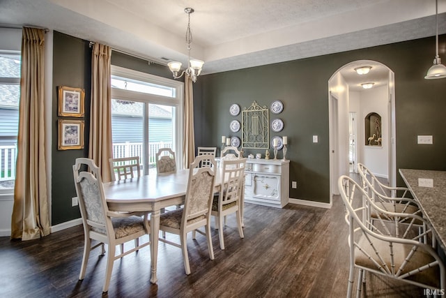 dining space with arched walkways, baseboards, dark wood-style flooring, and a chandelier
