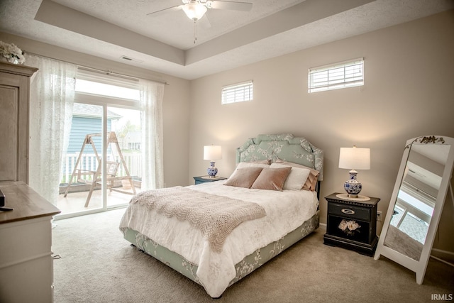 bedroom with carpet floors, access to outside, visible vents, and a raised ceiling