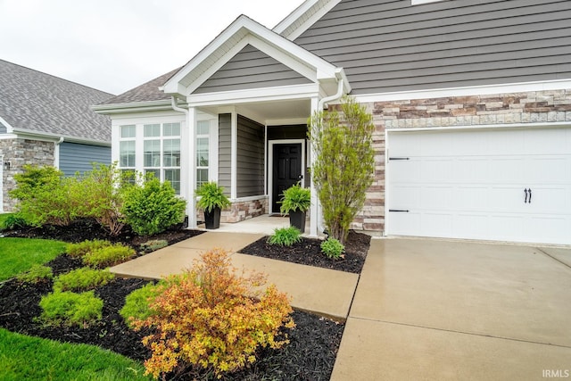 property entrance with concrete driveway, stone siding, and a garage