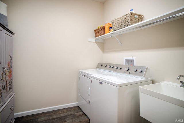 washroom featuring baseboards, dark wood-type flooring, washing machine and clothes dryer, a sink, and cabinet space