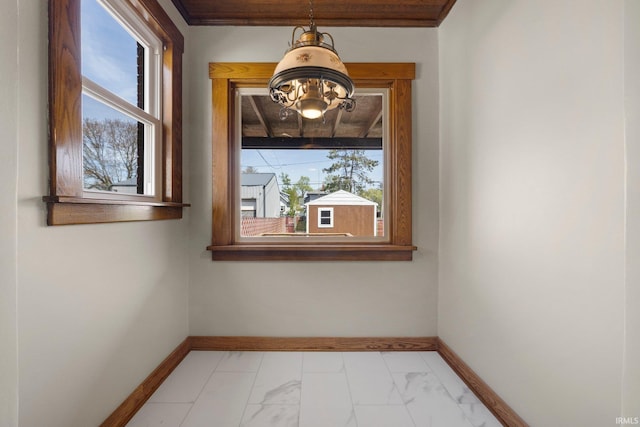 unfurnished room with baseboards, marble finish floor, and a notable chandelier