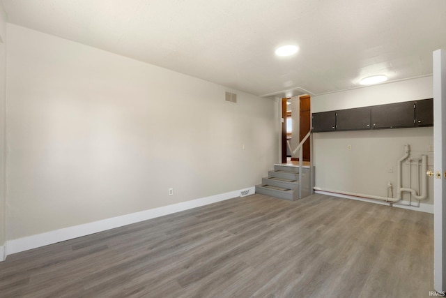 basement with visible vents, stairs, light wood-style floors, and baseboards