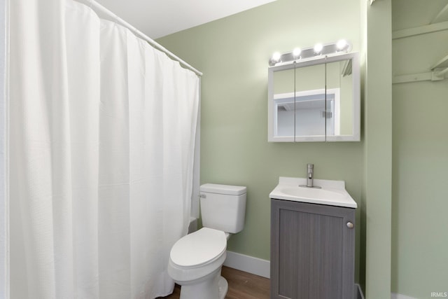 bathroom featuring toilet, baseboards, wood finished floors, and vanity