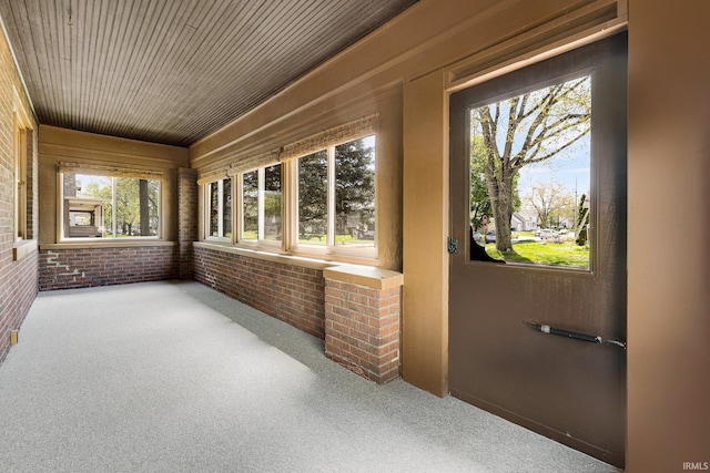 unfurnished sunroom with brick wall